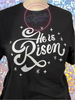 Black tee with He Is Risen in white glitter vinyl.