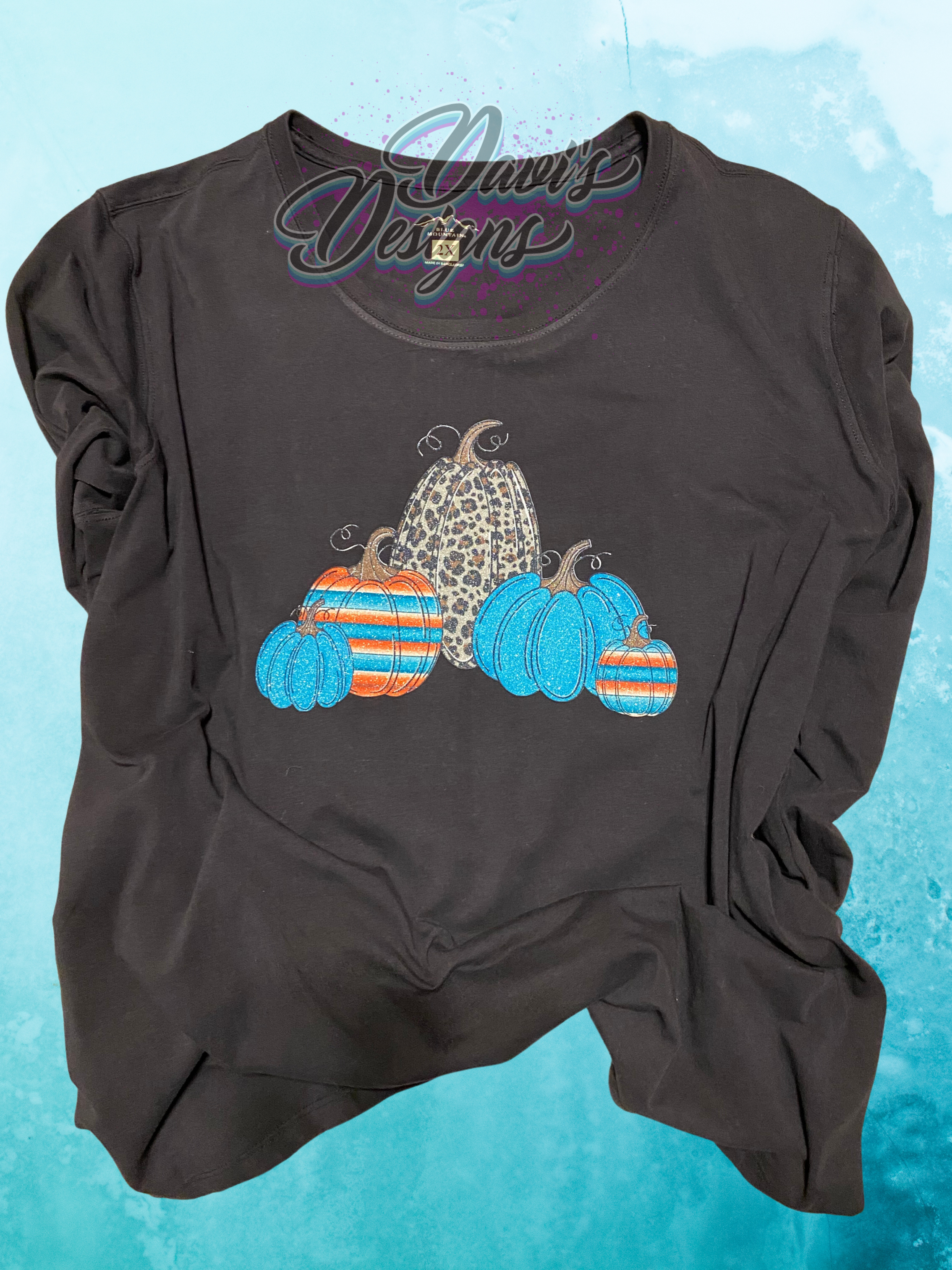 Black tee with five teal, orange, striped, leopard print pumpkins.