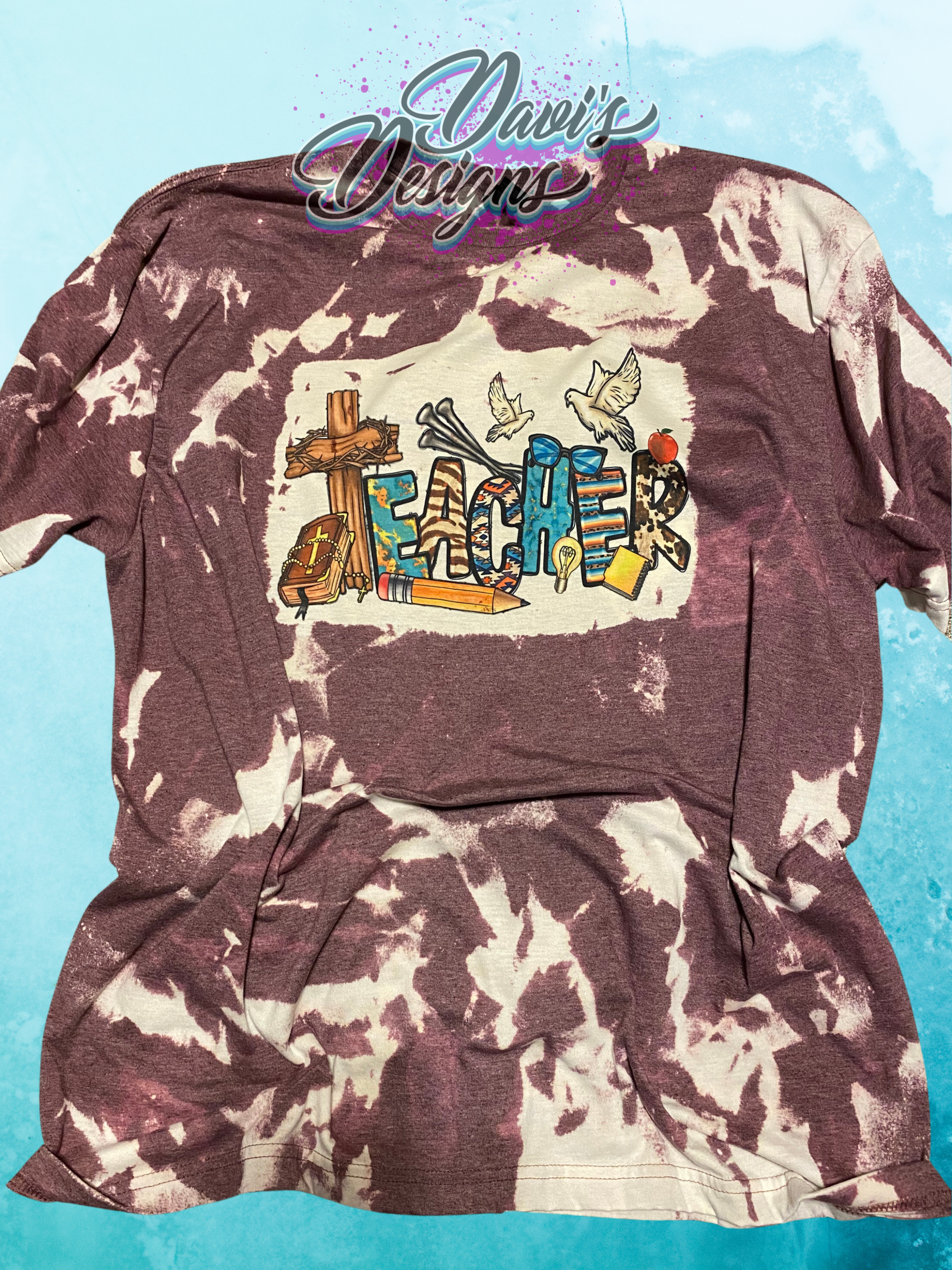 Heather Maroon bleach patterned tee with the word Teacher spelled with a cross for the T surrounded by Christian themed items.